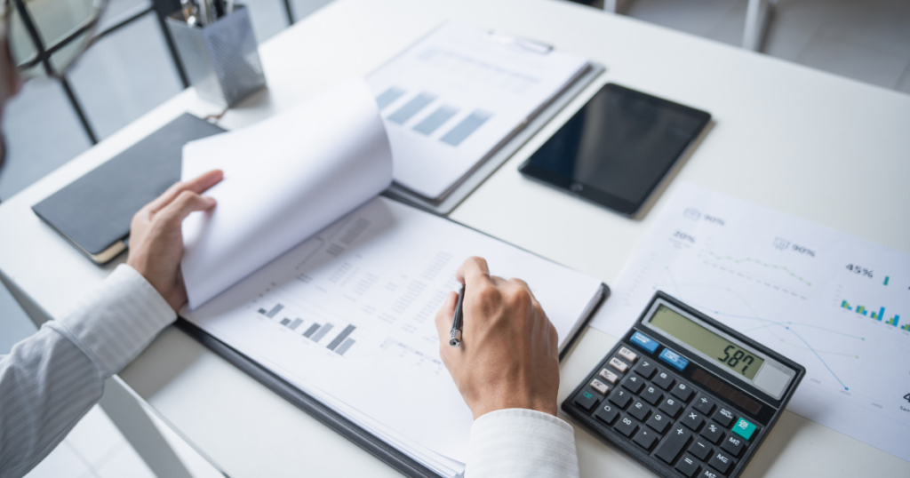 small business owner reviewing financial reports and using calculator for accounting and tax planning decisions