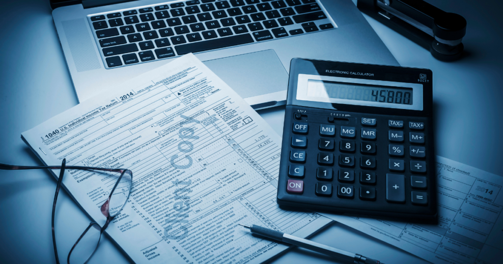 Small business tax preparation with tax forms, calculator, laptop, and financial records
