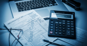 Small business tax preparation with tax forms, calculator, laptop, and financial records